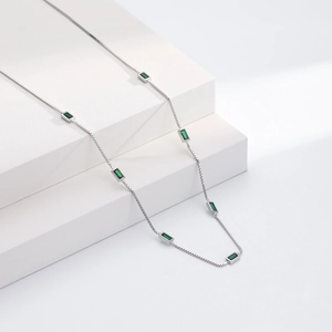 Detail of silver box chain necklace with baguette-cut emerald green zircon stones