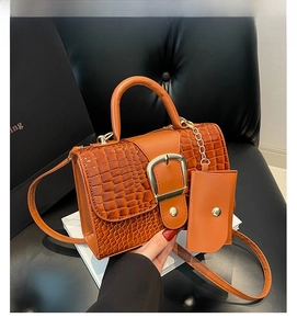 Détail du sac marron texture crocodile avec boucle dorée et mini porte-monnaie