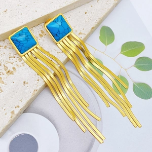 Detailed close-up of golden tassel earrings with turquoise stones on artistic background