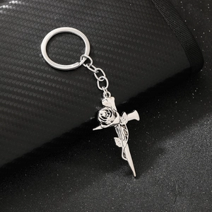 Macro detail of gothic silver keychain featuring a cross entwined with a rose design