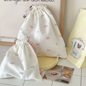 Detail of cream cotton drawstring bags with pink bow print in two various sizes