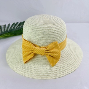 Detail of beige woven straw hat featuring a yellow striped ribbon bow for sun protection