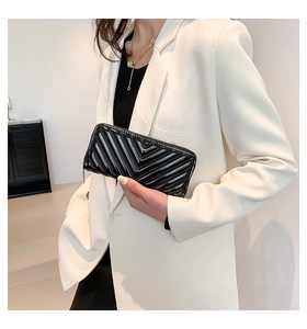Pochette chic en cuir verni noir avec matelassage en V tenue par un mannequin en blanc
