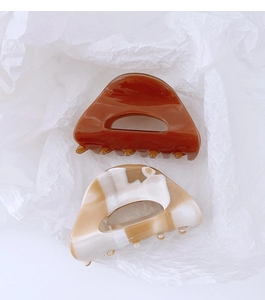Detail of tortoiseshell and marble texture acetate hair claws on white textured background