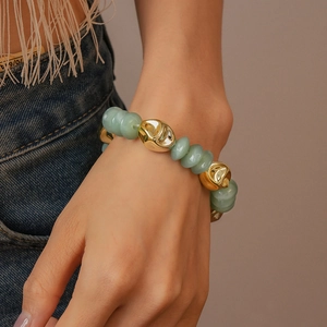Close-up of light green acrylic beads and irregular gold metal accents on a stylish bracelet