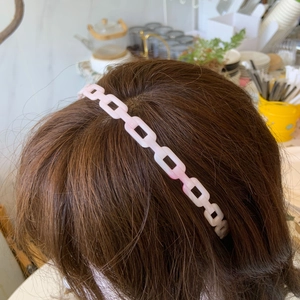 Close-up of pink acetic acid cube chain headband worn on hair with minimalist geometric style