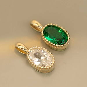 Macro shot of silver bracelets featuring oval emerald and white crystals with gold plating