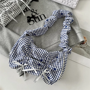 Close-up of blue and white checkered crossbody bag with white bow accents and ruched straps