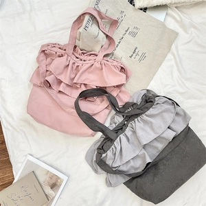 Detail of canvas tote bags with ruffled edges in dusty pink and muted grey colors