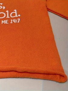Détail du pull en maille orange avec lettrage blanc imprimé Old ME 24:7 sur le devant