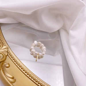 Detailed view of a handmade freshwater pearl ring with a dangling gold vertical charm