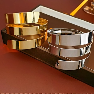 Detail of minimalist layered metallic bangle bracelets in polished gold and silver finish