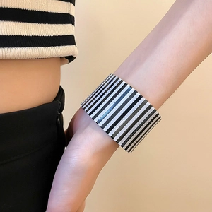 Close-up of a wide acrylic cuff bangle featuring classic black and white vertical stripes