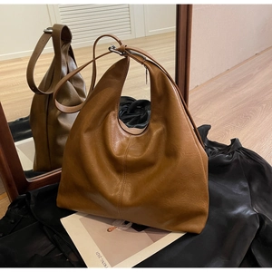 Detailed view of the large brown PU leather hobo bag on a natural wooden floor