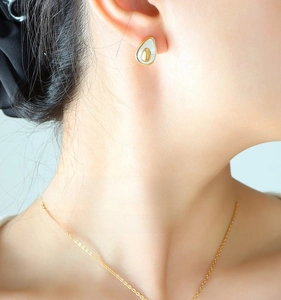 Detail view of gold-rimmed avocado necklace and earrings set worn by a female model