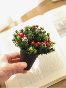 Close-up of a 13cm mini Christmas tree with red berries and pine cones in a black pot