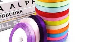 Macro detail of colorful 1cm satin ribbons stacked in rolls for DIY gift packaging
