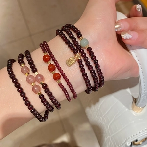 Close-up of layered garnet bracelet with strawberry quartz and golden Fu charm