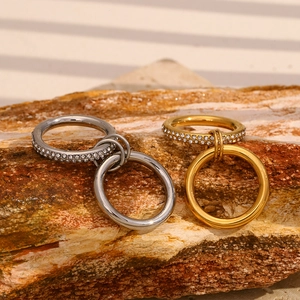 Close-up of double-layer stainless steel rings with zircons on a textured mineral stone