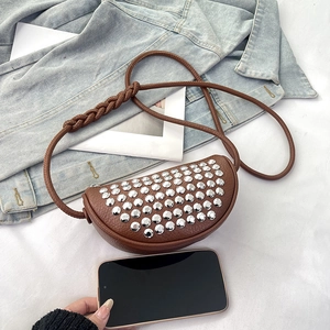 Brown studded crescent crossbody bag made of pebble leather on denim jacket