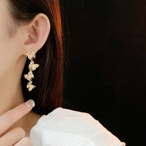 Close-up of elegant gold butterfly tassel earrings with zircon inlay worn by a model