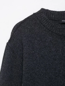 Detailed view of dark grey knitted sweater neckline with ribbed texture and soft wool blend
