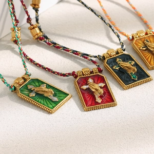 Detail of colorful woven cord necklaces with 18K gold plated cross and praying hands pendants