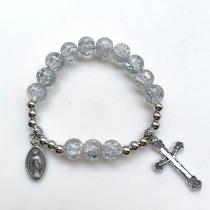 Dettaglio del bracciale con perle di vetro grigio crepato, croce d'argento e medaglie