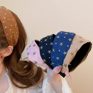 Détail d'un serre-tête en velours avec étoiles métalliques en plusieurs couleurs sur modèle