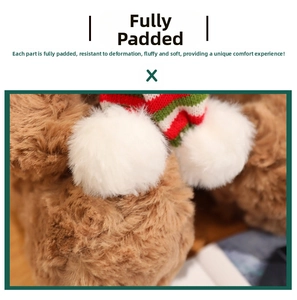 Close-up of brown plush teddy bear wearing a red and green striped knit scarf with pom-poms
