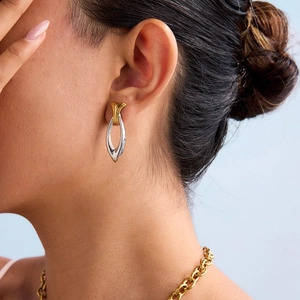 Two-tone stainless steel teardrop earrings with twisted design on model's ear