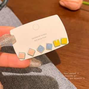 Detalle de seis pendientes cuadrados de colores con postes de plata S925 en tarjeta expositora