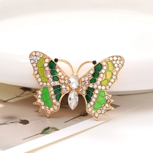 Macro detail of a zinc alloy butterfly accessory with crystals and green enamel