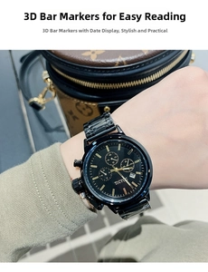 Detail of black chronograph watch with gold indices on a wrist beside a luxury bag