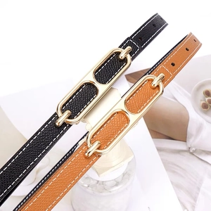 Slim leather belts in black and brown with gold double ring buckles on marble background