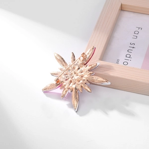 Back view of a star-shaped floral brooch with a silver and pink metal pin fastening