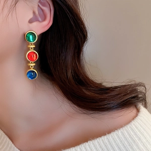 Gros plan de boucles d'oreilles vintage en or avec pierres multicolores sur modèle