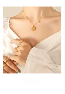 Detail of gold-plated jewelry set featuring engraved pendant necklace and stacked rings