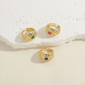 Three gold zircon band rings with green pink and blue stones on white stone