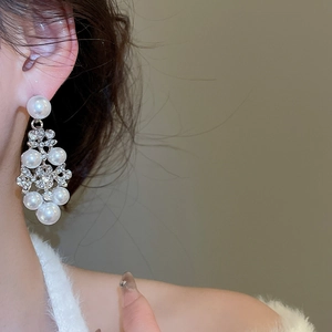 Gros plan de boucles d'oreilles fleurs élégantes avec perles et strass portées par un mannequin