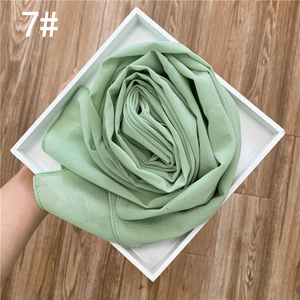 Détail du hijab en mousseline vert menthe avec paillettes dorées plié en fleur