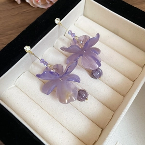 Detail of purple resin flower earrings with zirconia beads in a beige jewelry box