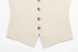 Détail du gilet en tricot beige avec boutons dorés élégants et ourlet fendu en forme de V