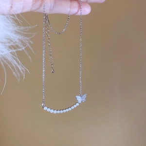 Close-up of 18k gold plated butterfly pendant with zircon and white pearls on silver chain