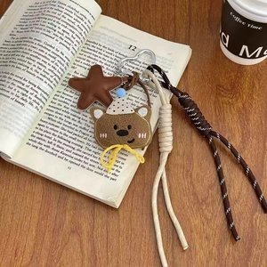 Plush brown bear keychain with star pendant on a book background with warm lighting