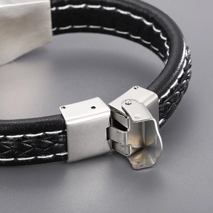Close-up of the mechanical folding clasp on a black braided leather survival bracelet