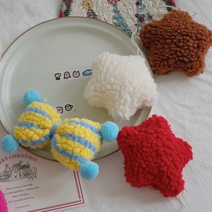 Close-up of plush lamb wool star and bow Christmas ornaments on a white plate
