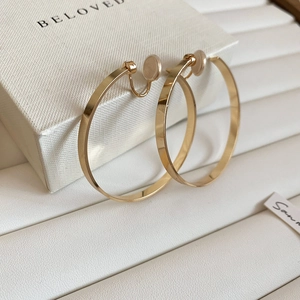 Detailed macro view of wide gold hoop clip earrings with silicone pads for non-pierced ears