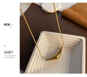 Détail d'un collier chaîne serpent dorée minimaliste avec un pendentif incurvé et élégant