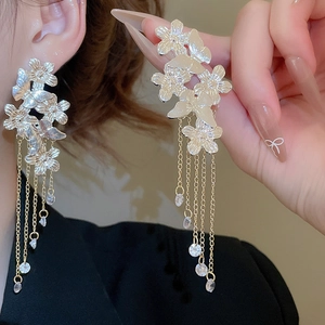 Macro shot of silver needle tassel earrings with butterfly floral charms and crystals